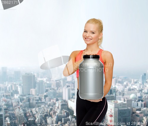 Image of smiling sporty woman with jar of protein