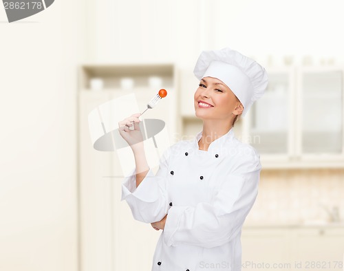 Image of smiling female chef with fork and tomato