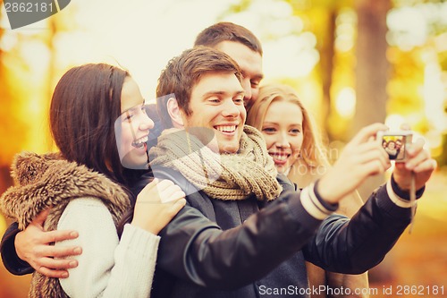 Image of group of friends with photo camera in autumn park