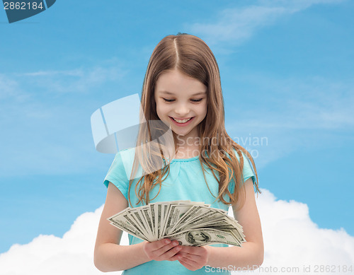 Image of smiling little girl looking at dollar cash money