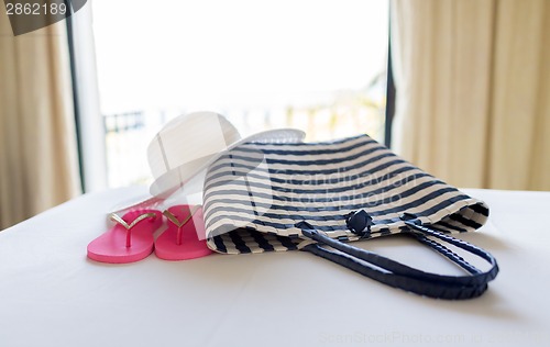 Image of close-up of beach bag, hat and flip-flop on bed