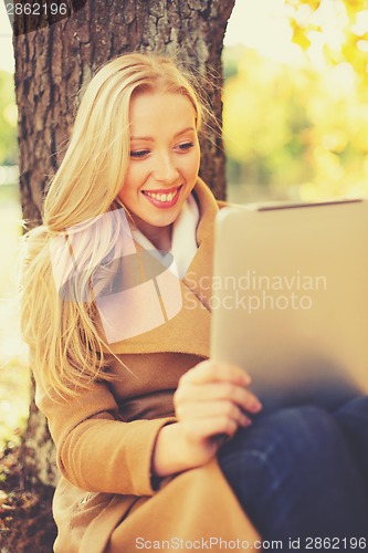 Image of woman with tablet pc in autumn park