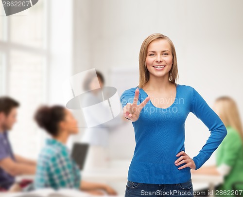 Image of smiling teenage girl showing v-sign with hand