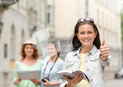 Image of smiling teenage girls with city guide and camera