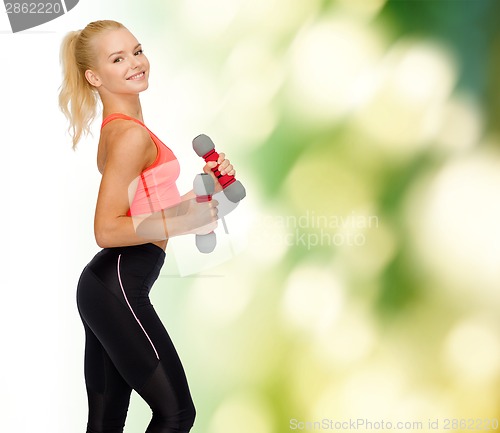 Image of smiling beautiful sporty woman with dumbbells