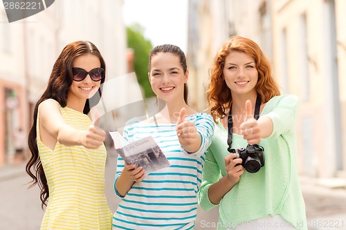 Image of smiling teenage girls with city guide and camera