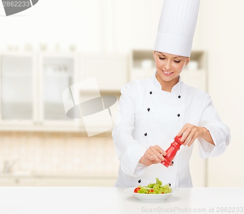 Image of smiling female chef with preparing salad