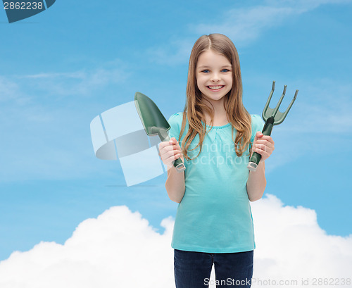 Image of smiling little girl with rake and scoop