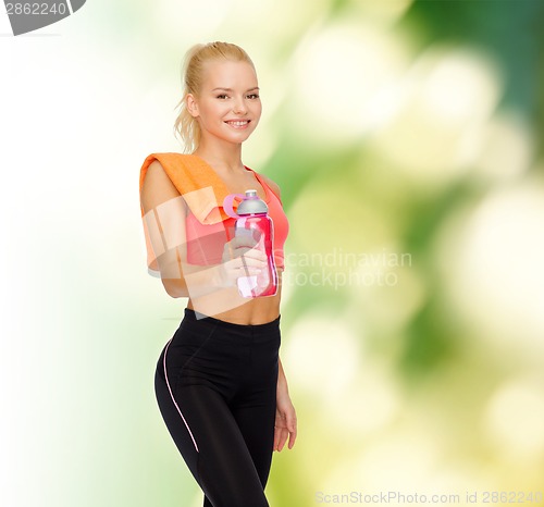 Image of smiling sporty woman with water bottle and towel