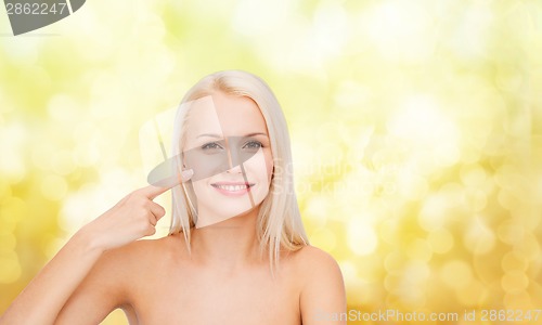 Image of smiling young woman pointing at her cheek