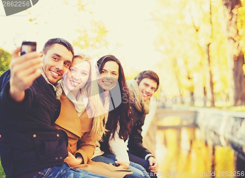 Image of group of friends taking selfie in autumn park