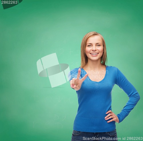 Image of smiling teenage girl showing v-sign with hand