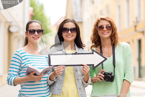 Image of smiling teenage girls with white arrow outdoors