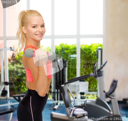 Image of smiling beautiful sporty woman with dumbbell