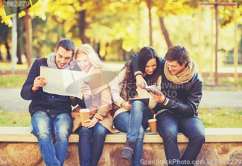 Image of couples with tourist map in autumn park