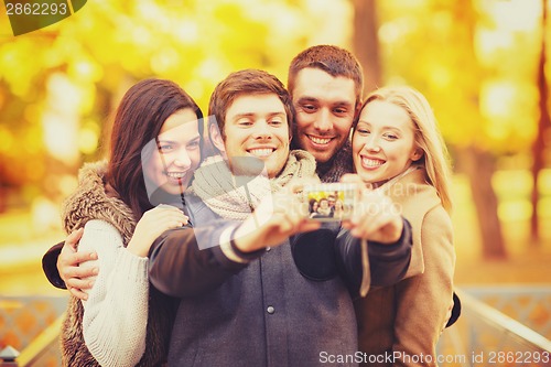 Image of group of friends with photo camera in autumn park