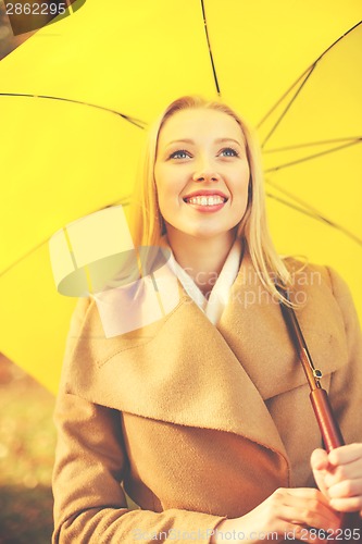 Image of woman with yellow umbrella in the autumn park