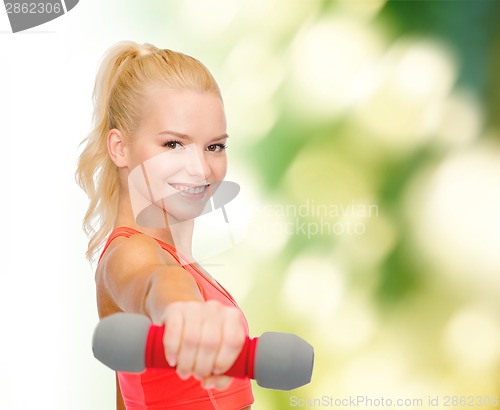 Image of smiling beautiful sporty woman with dumbbell