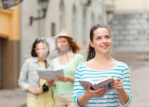 Image of smiling teenage girls with city guides and camera