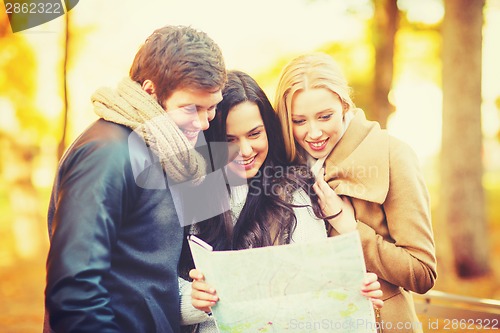 Image of friends with tourist map in autumn park