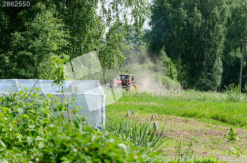 Image of small red tractor harrow ground  near homestead 