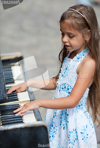 Image of Little girl playing on a piano