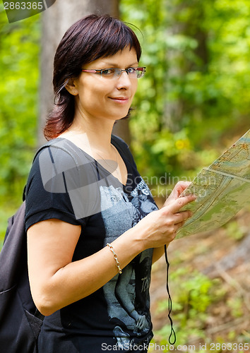 Image of Lost smilling woman in the countryside holding a map