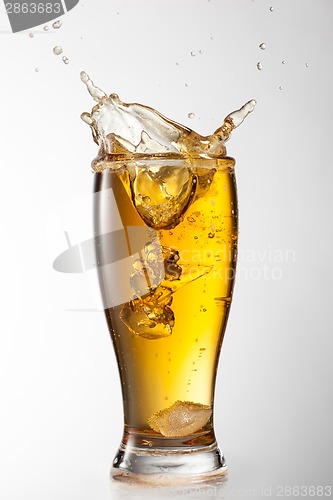 Image of Ice falling into beer glass with splash isolated