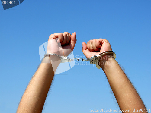 Image of The hands of the men chained in handcuffs, on a background of th