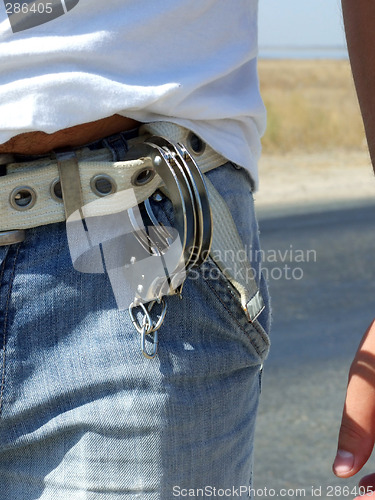 Image of The handcuffs hanging on a belt of jeans