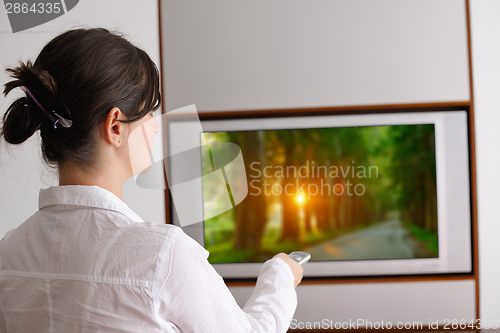 Image of young woman watching tv at home