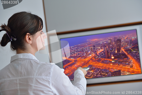 Image of young woman watching tv at home