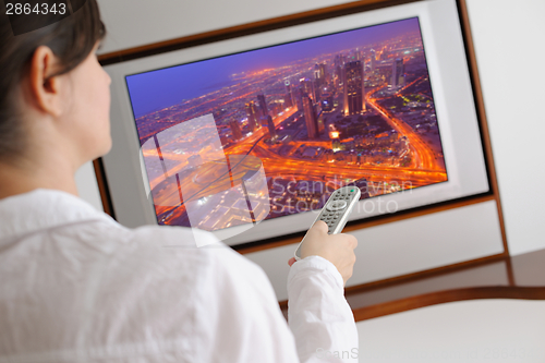 Image of young woman watching tv at home