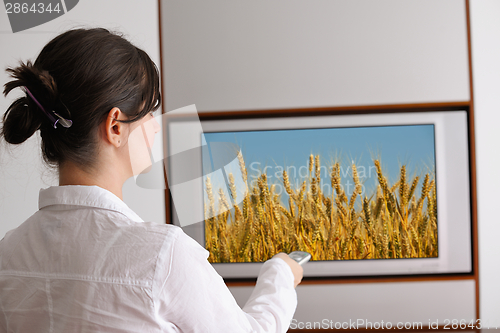 Image of young woman watching tv at home