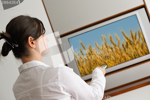 Image of young woman watching tv at home