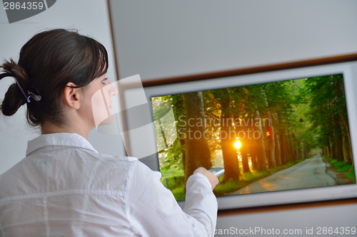 Image of young woman watching tv at home