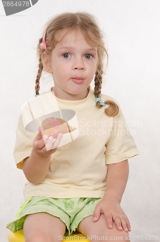 Image of Girl chews thoughtfully bun sitting on a chair