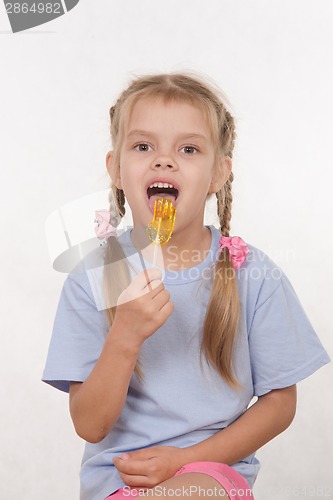 Image of Five year old girl licking a lollipop