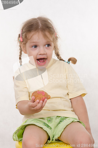 Image of The three-year girl laughing eating a bun