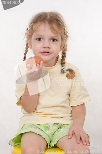 Image of Girl eating a bun sitting on chair