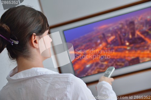 Image of young woman watching tv at home