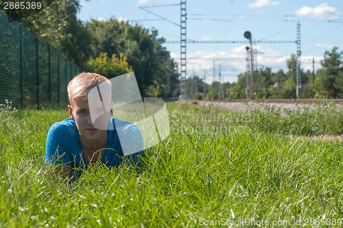 Image of Young man in blue lying on the green grass