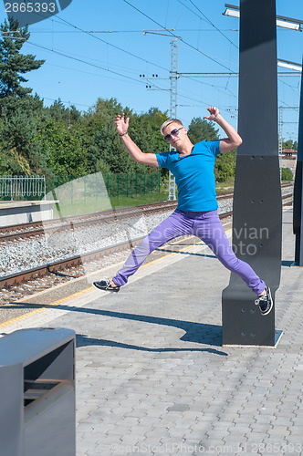 Image of Handsome young guy jumping on train station