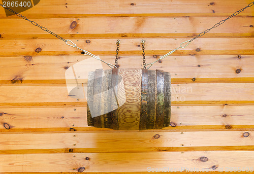 Image of gable of wooden rural house and barrel with chains 