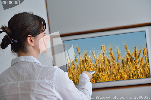 Image of young woman watching tv at home