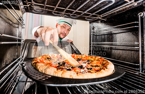 Image of Chef cooking pizza in the oven.