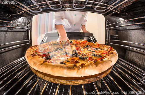 Image of Chef cooking pizza in the oven.