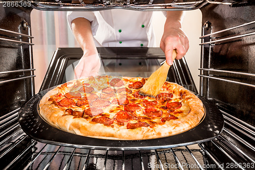 Image of Chef cooking pizza in the oven.