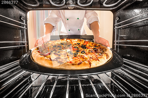 Image of Chef cooking pizza in the oven.