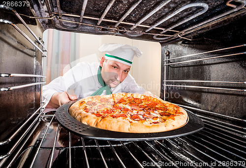 Image of Chef cooking pizza in the oven.